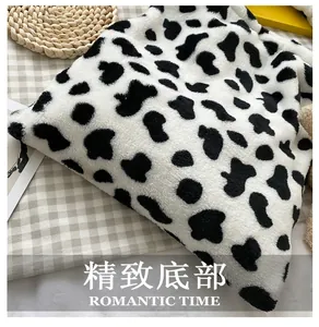 Detailed close-up showing the high-quality cow print plush texture and bottom stitching