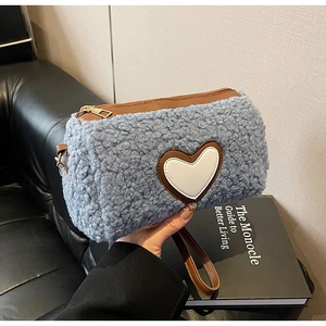 Dettaglio borsa in pile azzurro con finiture in pelle marrone e toppa a cuore bianca