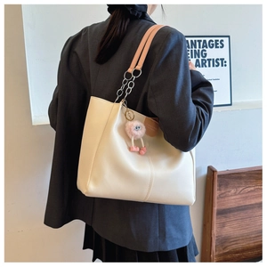 Detail of cream tote bag with pink leather chain strap and plush pendant decoration