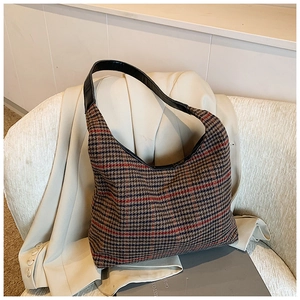 Detailed close-up of retro houndstooth pattern fabric and black leather shoulder strap