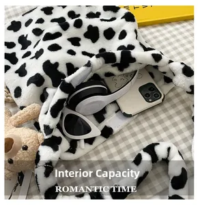 Internal capacity of cow print plush shoulder bag showing phone and headphones