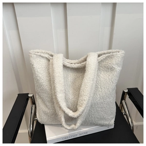 Close-up of a white plush tote bag with soft lamb wool texture on a minimalist chair