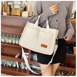 Close-up of white corduroy tote bag with double pockets and FASHION leather tag detail