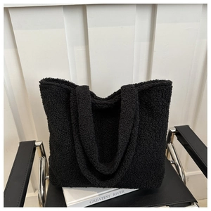 Detail of black fuzzy fleece tote bag placed on a designer chair in a minimalist room