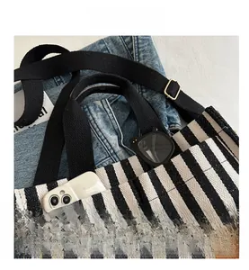 Detailed shot of striped canvas tote with smartphone and sunglasses in the front pocket