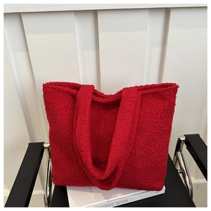 Detailed texture of a red plush fleece tote bag placed on white books in a cozy setting