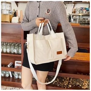 Detail of cream corduroy tote bag featuring large dual front pockets and brown leather label