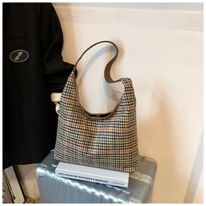 Detail view of houndstooth hobo bag on luggage with leather strap and woven texture