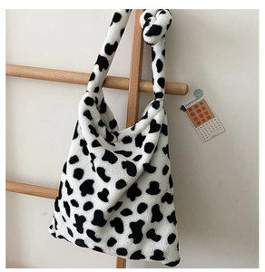 Detail of soft faux fur shoulder bag featuring black and white cow print and knotted strap