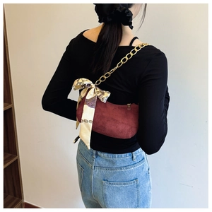 Detalle del bolso hobo de ante burdeos con cadena dorada y pañuelo de seda estampado