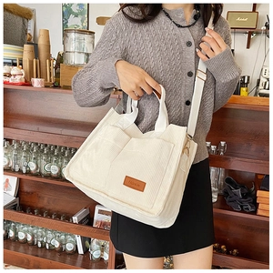 Detailed shot of white corduroy tote bag with front pockets and fashion leather label