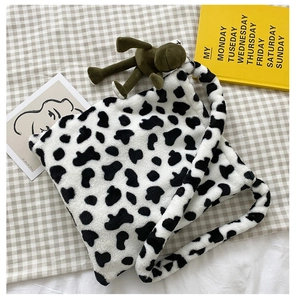 Detail of plush faux fur tote bag with cow print pattern and cute green frog charm accessory