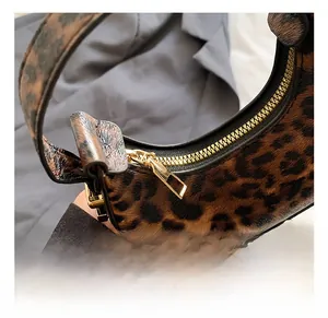 Close-up of golden metal zipper and leopard print texture on a fashion crescent bag