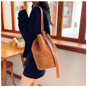 Detail view of caramel brown bucket bag with adjustable leather strap and matte suede texture
