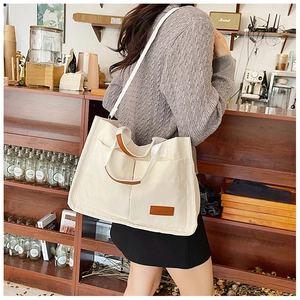 Close-up of beige corduroy tote bag showing dual front pockets and leather details