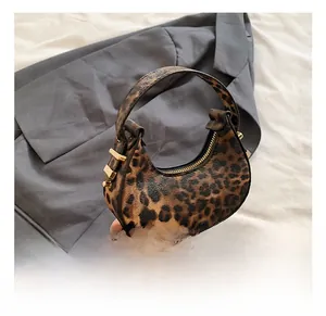 Detail shot of mini crescent bag featuring leopard print pattern and golden metal buckle