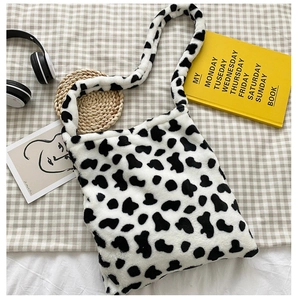 Detail of soft black and white cow print plush tote bag with wide comfort shoulder strap