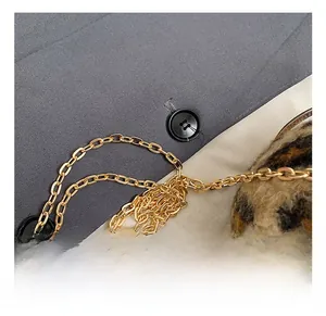 Détail de la bandoulière en chaîne dorée et du tissu en peluche léopard du mini sac