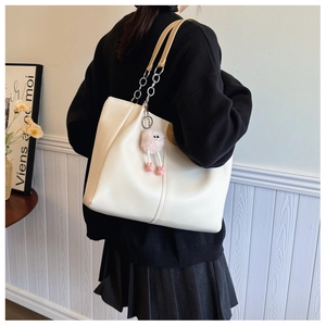 Chic off-white leather tote bag with metal chain strap and pink plush charm accessory