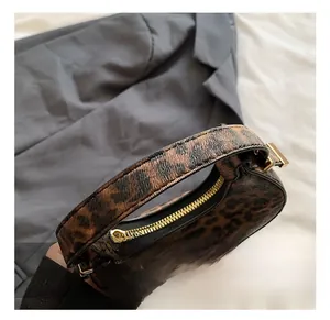 Close-up of leopard print crescent bag with golden zipper and smooth handle detail