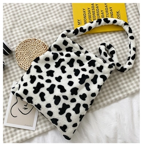 Close-up of fluffy cow print plush crossbody bag texture with a long shoulder strap