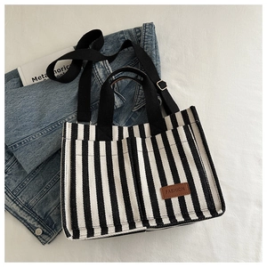 Detailed close-up of striped canvas tote bag with front pockets and leather fashion label