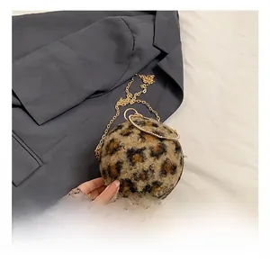 Détail du sac rond en peluche léopard avec poignée dorée et bandoulière sur blazer gris