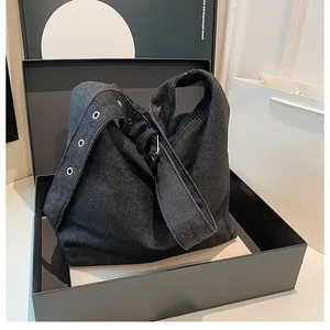 Détail du sac hobo en denim noir anthracite avec larges bandoulières et œillets métalliques