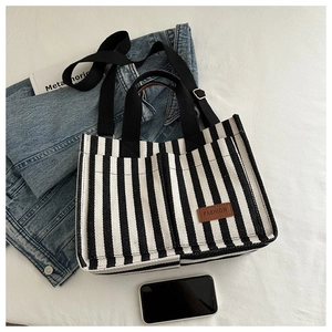 Detailed view of striped canvas tote with adjustable shoulder strap and leather patch