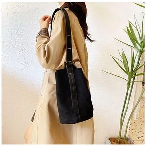 Detail view of large matte black bucket bag with smooth leather strap contrast for women