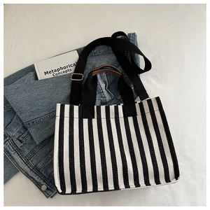 Flat lay of a striped canvas tote bag with adjustable shoulder strap and leather handles