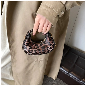 Detail of leopard print crescent bag featuring golden hardware and a premium zip closure