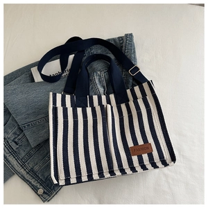 Detail of blue striped canvas tote showing pockets, leather label, and webbing handles