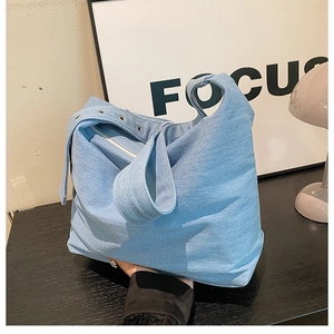 Détail de la bandoulière à œillets métalliques du sac hobo en jean bleu clair avec zip