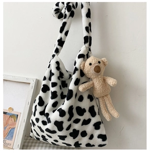 Detail of soft faux fur tote bag with cow print pattern and cute teddy bear charm
