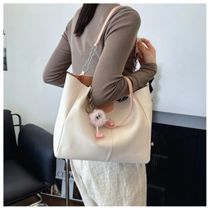 Close-up of beige tote bag showing high-quality leather texture and pink plush monster charm