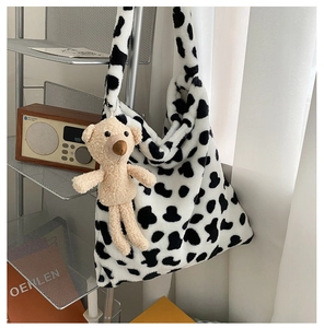 Detail of plush cow print hobo bag featuring a cute brown bear charm accessory