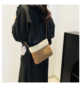 Detail view of the brown suede crossbody bag with white fleece trim and cute dog charm