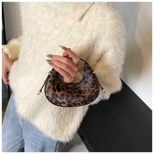 Macro detail of crescent handbag featuring leopard print and gold cylindrical hardware