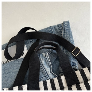Close-up of black and white vertical striped canvas tote bag with adjustable shoulder strap