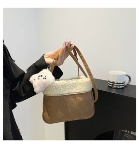 Close-up of suede and white sherpa patchwork shoulder bag with a cute bear charm