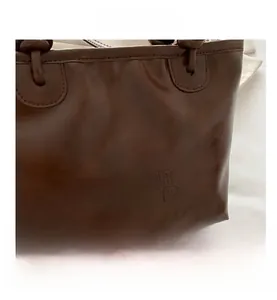 Detail of vintage brown leather tote bag showing MEIGE SNUR GOOD embossed lettering