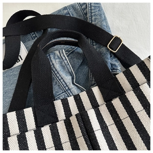 Detail of black and white striped canvas tote bag showing top strap and metal buckle