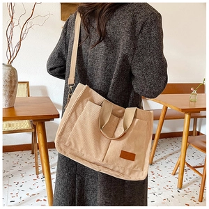 Detail of light beige corduroy tote bag showing textured stripes and brown leather logo tag