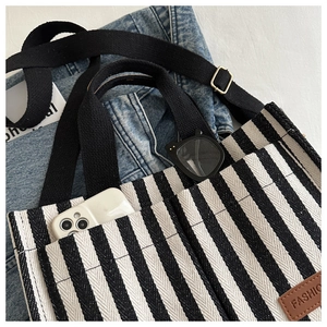 Detailed view of striped canvas tote with multiple pockets and durable shoulder strap