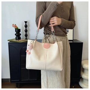 Detail of off-white leather tote bag with pink chain handle and plush ball charm