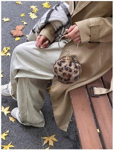 Mini sac boule léopard avec poignée en strass présenté dans un décor d'automne doré