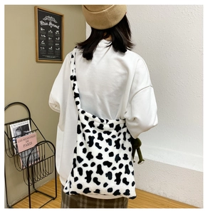 Detail view of cow pattern plush crossbody bag with soft faux fur texture shown on model