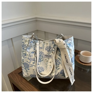 Close-up of floral print tote bag with metal chain handle and wide woven shoulder strap