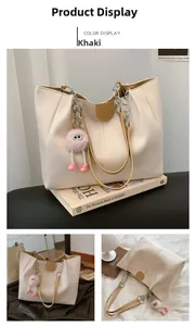 Detail view of khaki faux leather tote bag with metal chain strap and pink pom pom charm
